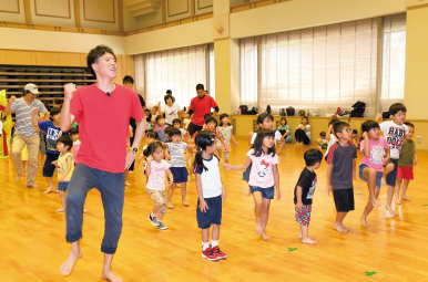 男性保育士と子どもたちがダンスをしている写真