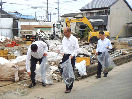 震災後解体現場の前でゴミ拾いの写真